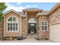 Inviting stone entry with arched window and well-manicured landscaping at 1251 Double Eagle Ct, Castle Rock, CO 80104