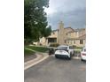 A well-maintained townhome with a stone chimney, visible parking, and green space at 8452 Everett Way # C, Arvada, CO 80005