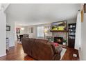 Comfortable living room featuring a stone fireplace, hardwood floors, and a view into the dining area at 8452 Everett Way # C, Arvada, CO 80005