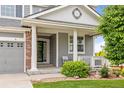 Inviting covered front porch with classic white columns and a cozy seating area at 16120 E 119Th Ave, Commerce City, CO 80022