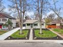 Charming single-story home featuring a manicured front yard and mature trees on a sunny day at 949 Pontiac St, Denver, CO 80220