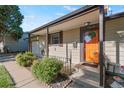 Inviting front porch featuring a bright orange door and lovely landscaping with a cute welcome sign at 7310 Granada Rd, Denver, CO 80221