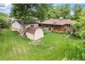 Expansive backyard with lush green grass, a storage shed, and mature trees at 1475 S Urban Way, Lakewood, CO 80228