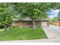 Charming single-story brick home with lush front lawn and mature shade tree, complemented by a paved driveway and attached garage at 1475 S Urban Way, Lakewood, CO 80228