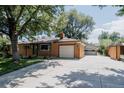 Charming brick home with mature trees, a well-maintained lawn, and a spacious driveway at 1475 S Urban Way, Lakewood, CO 80228