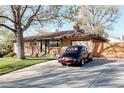 Charming brick home with a well-maintained front yard, mature tree, and a classic car parked in the driveway at 1475 S Urban Way, Lakewood, CO 80228