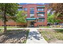 Exterior shot of the Grant Plaza apartment building, showcasing its red brick facade and well-maintained landscaping at 85 N Grant St # 28, Denver, CO 80203