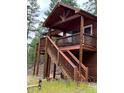 Charming cabin exterior featuring a rustic stairway leading to a spacious wooden deck at 9705 Canon Dr, Sedalia, CO 80135