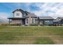 Inviting two-story home featuring a covered porch, stone chimney, and well-maintained lawn at 2611 Prairie Flax St, Berthoud, CO 80513