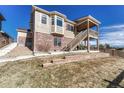Inviting backyard featuring a two-story deck with wooden stairs, red shutters, and landscaped surroundings at 4883 S Sicily St, Aurora, CO 80015