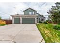 Charming two-story home showcases a three-car garage, green siding, and stone accents, set on a lush lawn at 21396 E Prentice Ln, Centennial, CO 80015