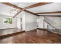 Open-concept living room featuring a vaulted ceiling, wood beam accents, hardwood floors, and a staircase nearby at 8727 E Girard Ave, Denver, CO 80231