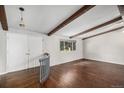 Bright living room featuring hardwood floors, wood beam ceiling accents, and a large window providing natural light at 8727 E Girard Ave, Denver, CO 80231