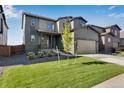 Two-story home with a lawn, two car garage, and newly planted tree at 13398 E 99Th Pl, Commerce City, CO 80022