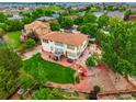 Aerial view of a sprawling backyard with mature trees, patio area, and lush lawn at 16650 E 107Th Ct, Commerce City, CO 80022