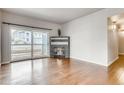 Living room with fireplace and hardwood floors, view of kitchen and patio at 8437 Thunder Ridge Way # 102, Highlands Ranch, CO 80126