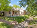Quaint home with inviting front porch, complemented by lush greenery and a charming brick wall at 3929 Shoshone St, Denver, CO 80211