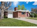 A single-story brick home featuring an attached garage and a well-manicured lawn at 8209 Benton Way, Arvada, CO 80003