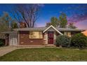 Charming brick home with a well-manicured lawn, complemented by mature trees and a colorful sunset at 8209 Benton Way, Arvada, CO 80003