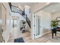 Bright entryway features a soaring ceiling, hardwood floors, decorative table, and an open staircase at 12762 Bend Ct, Firestone, CO 80504
