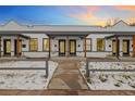 Charming row of townhomes featuring white brick, dark trim, a small porch and a shared walkway at 3005 California St, Denver, CO 80205