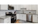 Modern kitchen with white cabinets, stainless steel appliances, and herringbone backsplash at 3005 California St, Denver, CO 80205