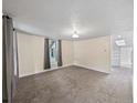Spacious living area with neutral carpet and paint, plus a glimpse into the kitchen and hallway at 4232 S Grant St, Englewood, CO 80113