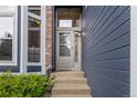 View of the home's front door with an adjacent brick siding and a small patch of decorative plant life at 1412 Pinyon Dr, Castle Rock, CO 80104