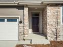 Front entrance with stone facade, dark door, and covered porch at 1927 S Coolidge Way, Aurora, CO 80018