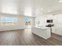 Open concept kitchen with white cabinets, island, and stainless steel appliances at 1927 S Coolidge Way, Aurora, CO 80018