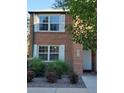 Classic brick townhouse features updated windows with white shutters, and manicured shrubs at 2813 Jasmine St, Denver, CO 80207