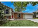 Charming home featuring a red door, brick accents, well-maintained lawn, and mature trees at 117 Sandler Dr, Lafayette, CO 80026
