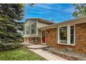 Charming home featuring a red door, brick accents, and well-maintained landscaping at 117 Sandler Dr, Lafayette, CO 80026
