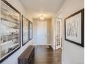 Inviting hallway with dark wood floors, neutral walls, decorative art, and a view of the front door at 11096 Endeavor Dr, Parker, CO 80134