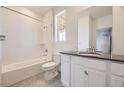 Bathroom featuring white cabinets, shower-tub, and tiled floor with a black countertop at 2188 S Haleyville Way, Aurora, CO 80018