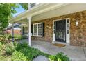 Inviting covered porch featuring stone accents, a porch swing, and ornate metalwork at 3884 S Niagara Way, Denver, CO 80237
