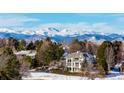 A beautiful multi-level house with mountain views, nestled among lush evergreens in a snowy landscape at 93 Glenmoor Dr, Cherry Hills Village, CO 80113