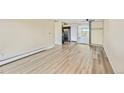 Open-concept living room with wood-look flooring, stainless appliances, and sliding glass doors to the balcony at 4110 Hale Pkwy # 5F, Denver, CO 80220