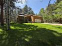 Lovely exterior featuring a two-car garage, complemented by a well-maintained lawn and towering trees at 85 S Sherwood Gln, Monument, CO 80132