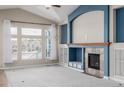 Bright living room featuring a gas fireplace, built-in shelving, and large windows with beautiful neighborhood views at 8802 E 148Th Ln, Thornton, CO 80602