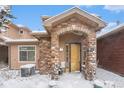 Townhome's front entrance with stone archway, snowy landscaping at 8551 Gold Peak Dr # B, Highlands Ranch, CO 80130