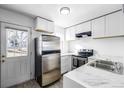 Modern kitchen with stainless steel appliances, white cabinets, marble countertops, and natural light from the backyard at 3281 S Estes St, Lakewood, CO 80227