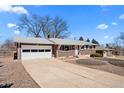 Brick home featuring an attached garage and a well-kept front yard with mature landscaping at 12087 W New Mexico Ave, Lakewood, CO 80228