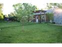 Expansive backyard featuring lush lawn, garden space, mature trees, and a charming pergola at 1047 Scranton St, Aurora, CO 80011