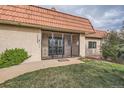 Home featuring an ornate iron security gate, mature lawn, and unique terracotta tiled roof at 7720 W Quincy Dr, Lakewood, CO 80235