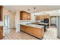 Spacious kitchen with granite countertops, wood cabinetry, a center island and tile floors at 7720 W Quincy Dr, Lakewood, CO 80235