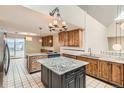 Bright kitchen featuring granite countertops, wood cabinetry, a center island and stainless appliances at 7720 W Quincy Dr, Lakewood, CO 80235