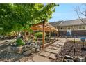Captivating backyard featuring a rock water feature, wood pergola, stone pathway, mature trees and manicured shrubbery at 7600 Kline Dr, Arvada, CO 80005