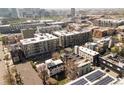 An aerial view shows modern city apartment buildings in a neighborhood with solar panels, and a distant city skyline at 1749 Boulder St, Denver, CO 80211
