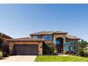 Elegant two-story home featuring stone accents, manicured lawn, and an attached two-car garage at 12457 Topaz Vista Way, Castle Pines, CO 80108